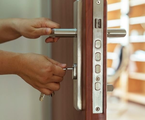 Hand dreht Schlüssel im Schloss einer Holztür